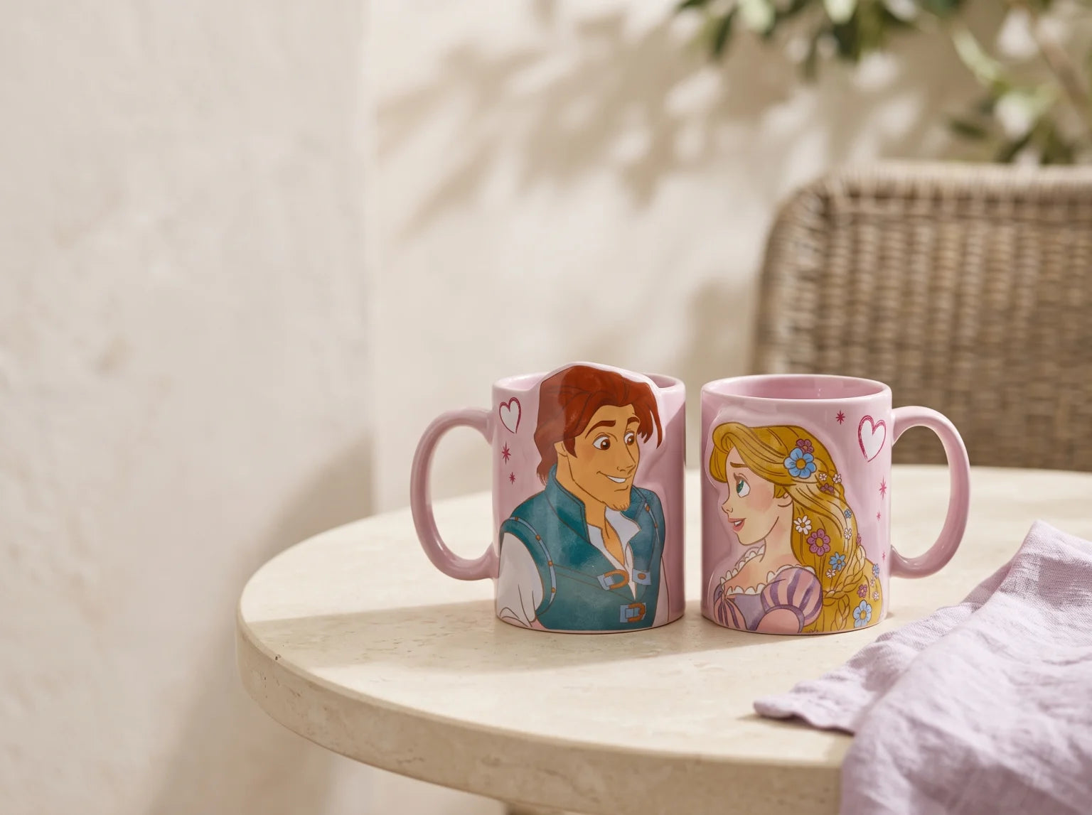 Tazas Rapunzel y Flynn en una terraza luminosa, sobre una mesa de piedra y junto a lino lavanda