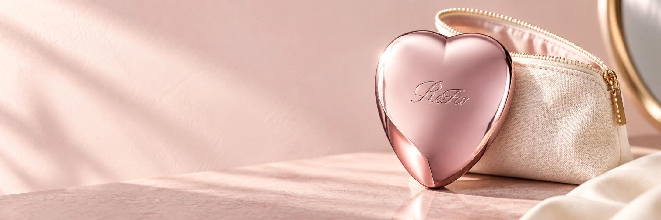 ReFa Heart Brush oro rosa junto a un cosmetiquero marfil, sobre un tocador rosado con luz de mañana